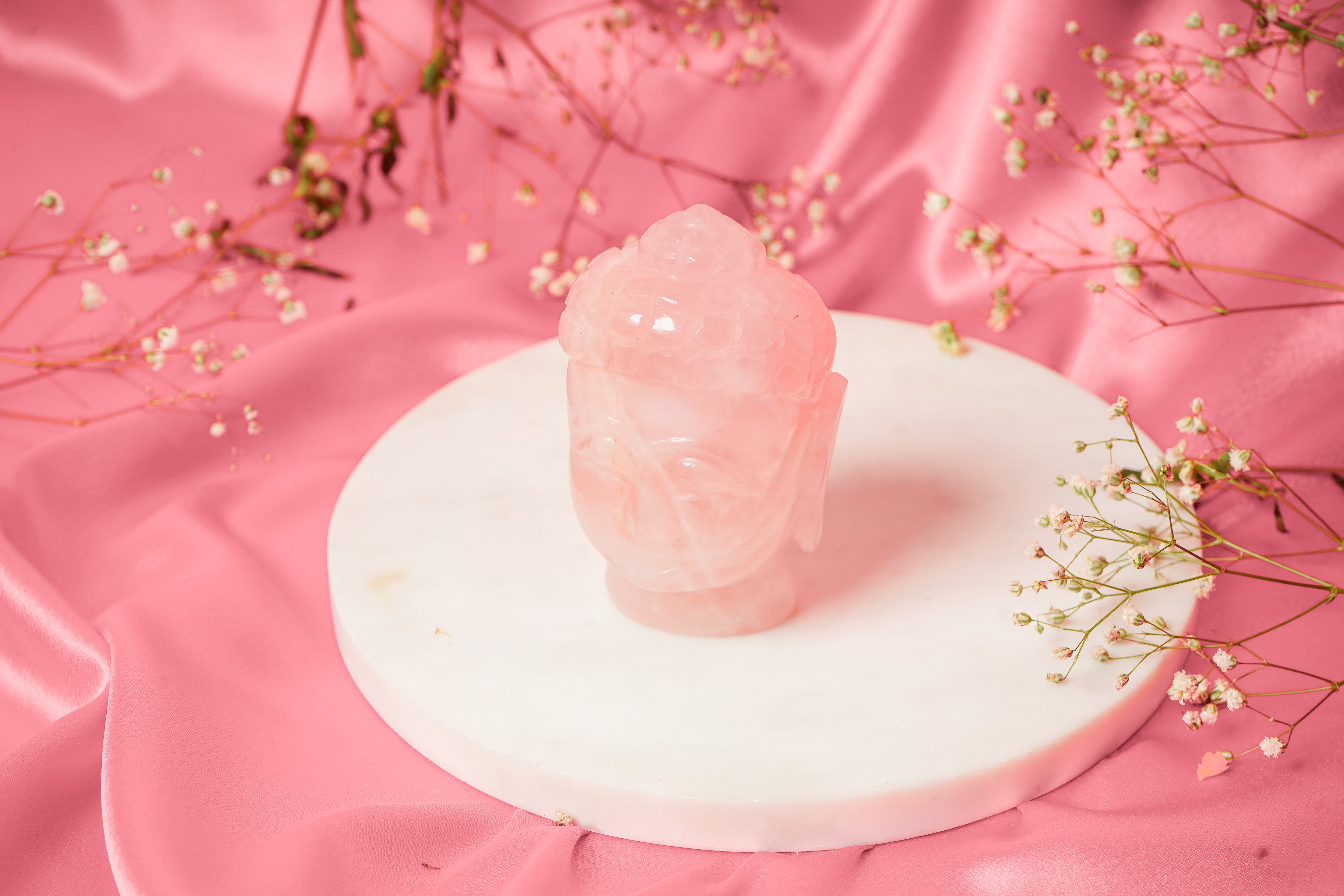 Natural rose quartz Buddha head sculpture with smooth, polished surface and serene facial expression, decorative meditation decor.