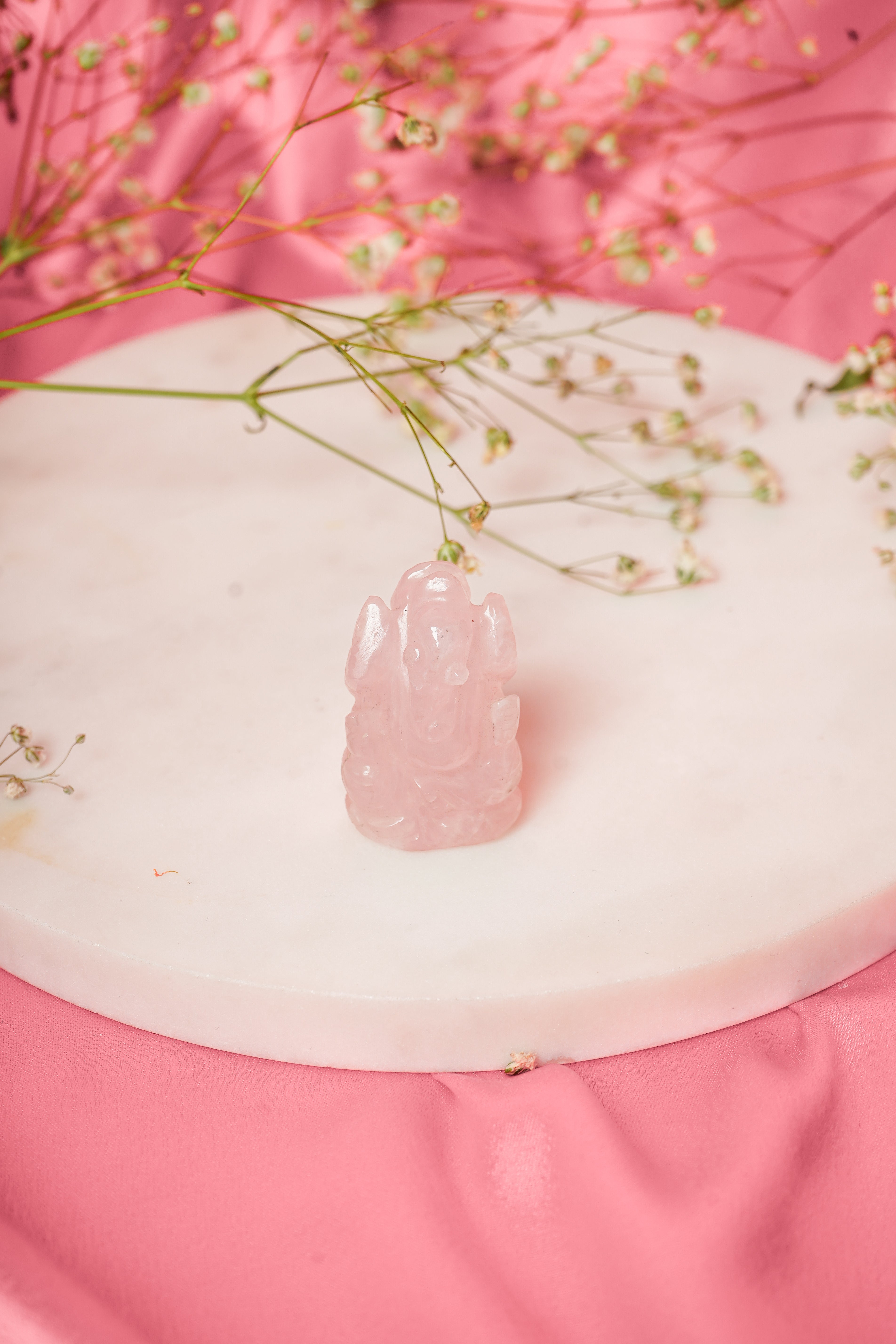 Natural rose quartz Ganesh ji statue with detailed carvings, representing the Hindu deity Ganesha in a serene pose.