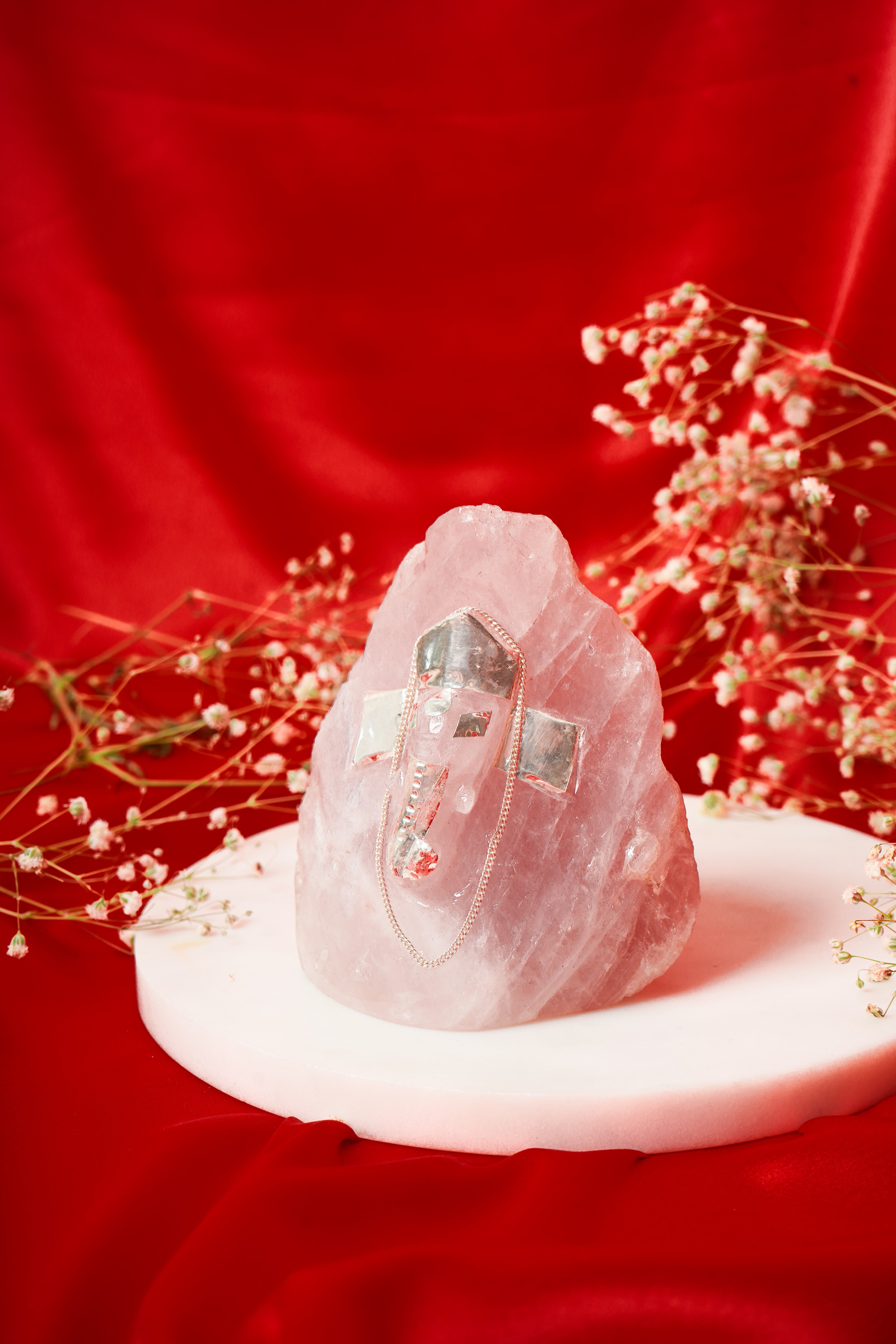 Natural rose quartz Ganesh ji sculpture with silver accents, unshaped form, showcasing intricate details and craftsmanship.