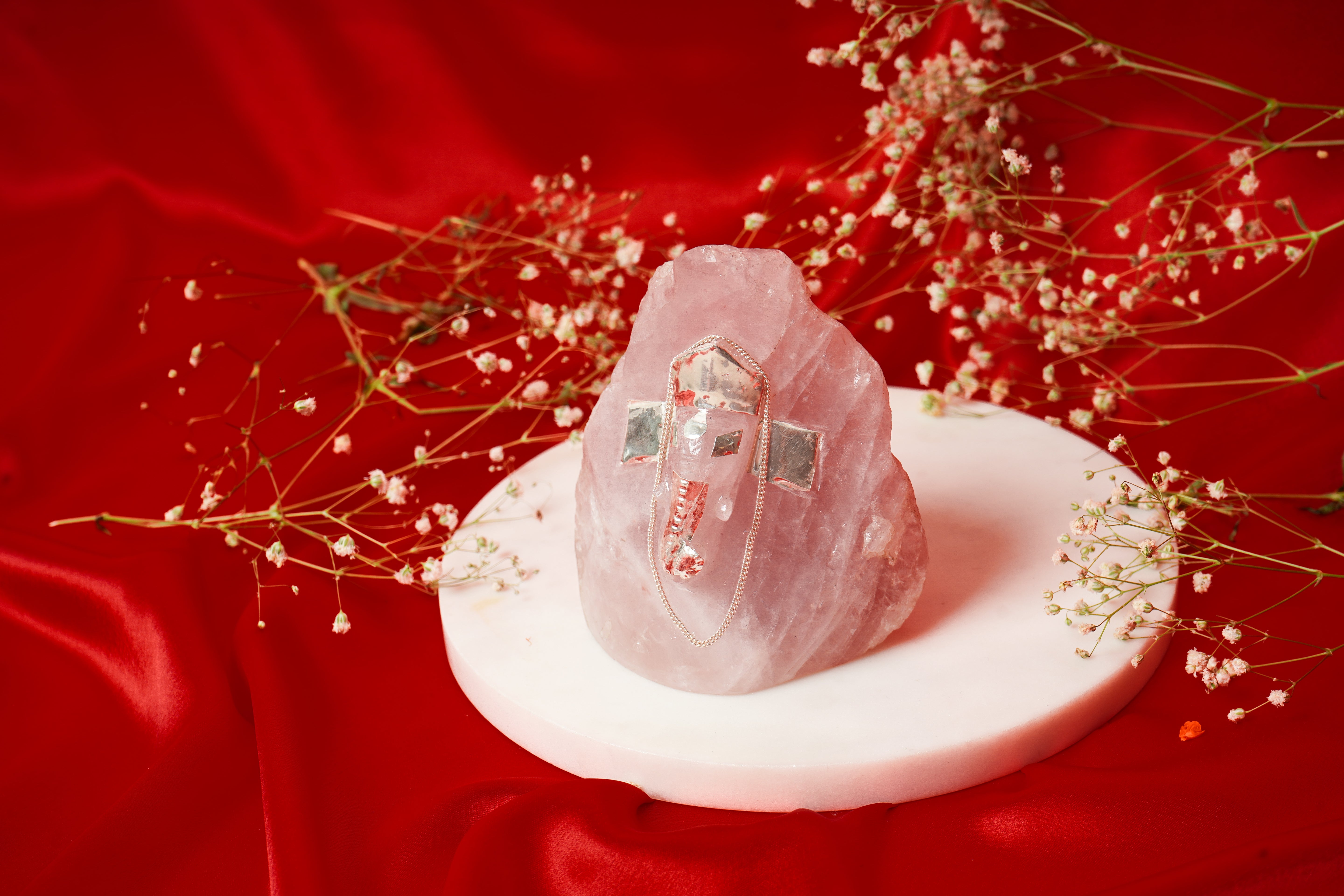Unshaped natural rose quartz Ganesh ji with silver accents, featuring a carved Hindu deity figure for spiritual decor.