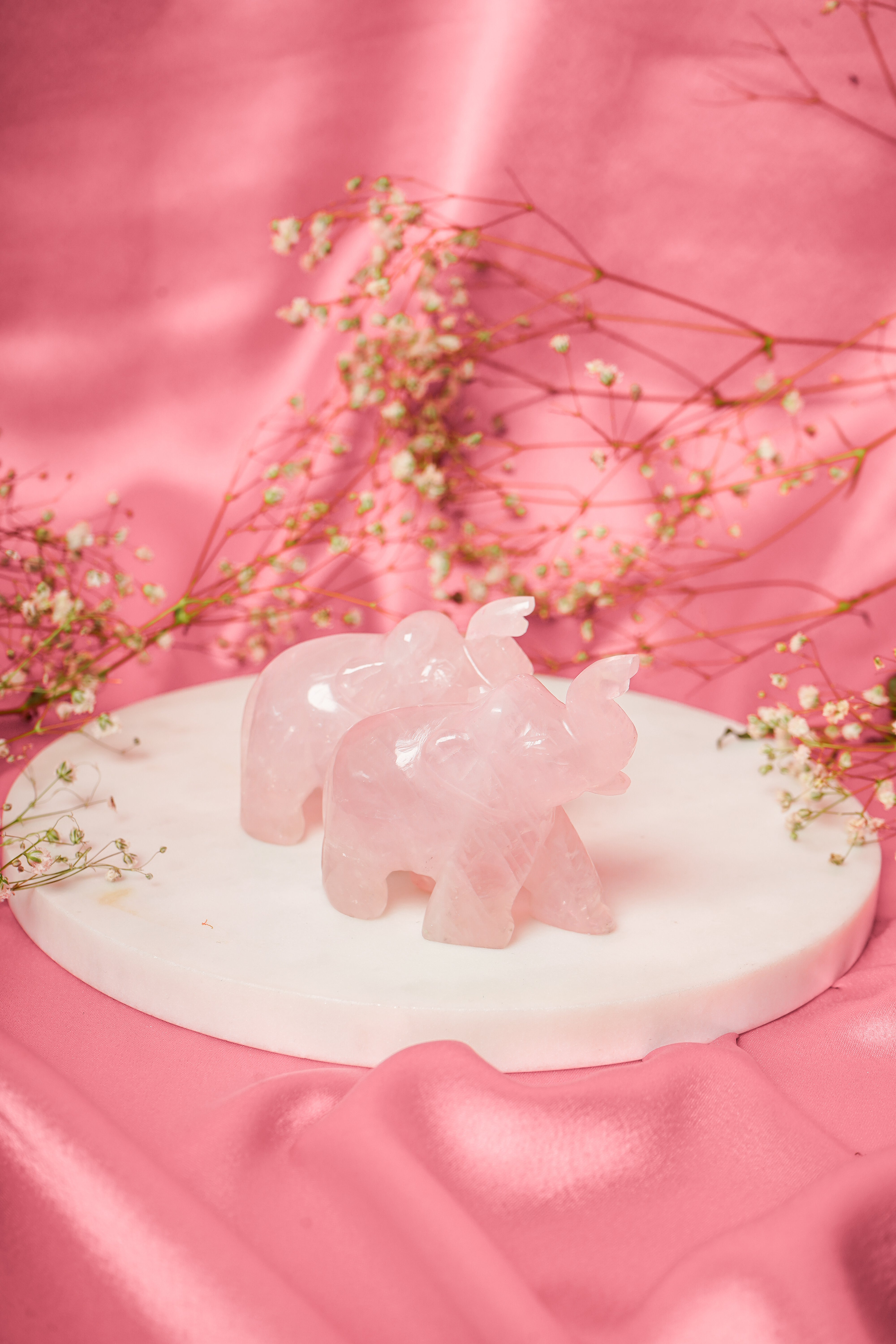 Pair of natural rose quartz elephant figurines with carved details, showcasing pink semi-precious stone and intricate craftsmanship.