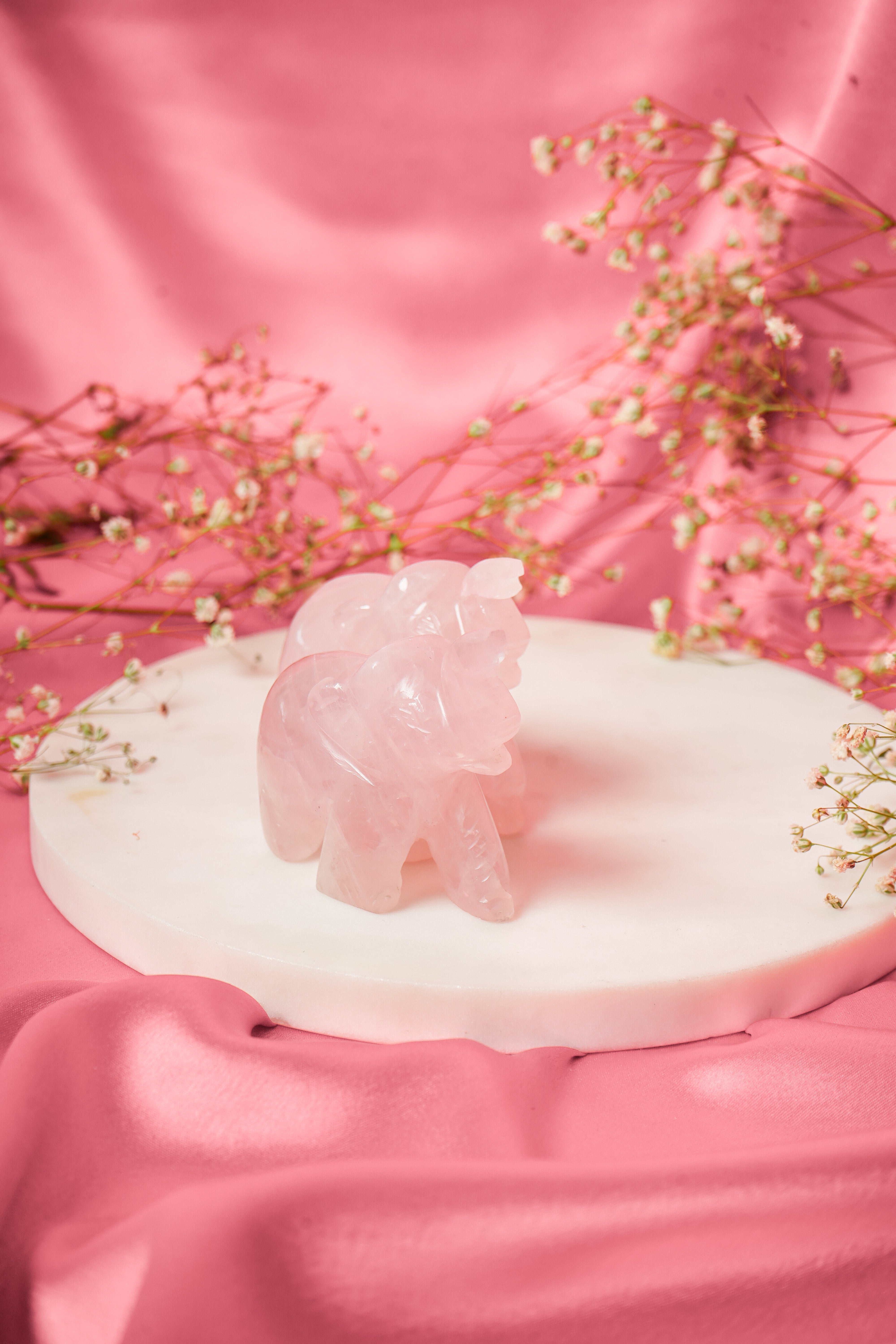 Pair of natural rose quartz elephant figurines with detailed carvings, showcasing soft pink stones and intricate craftsmanship.
