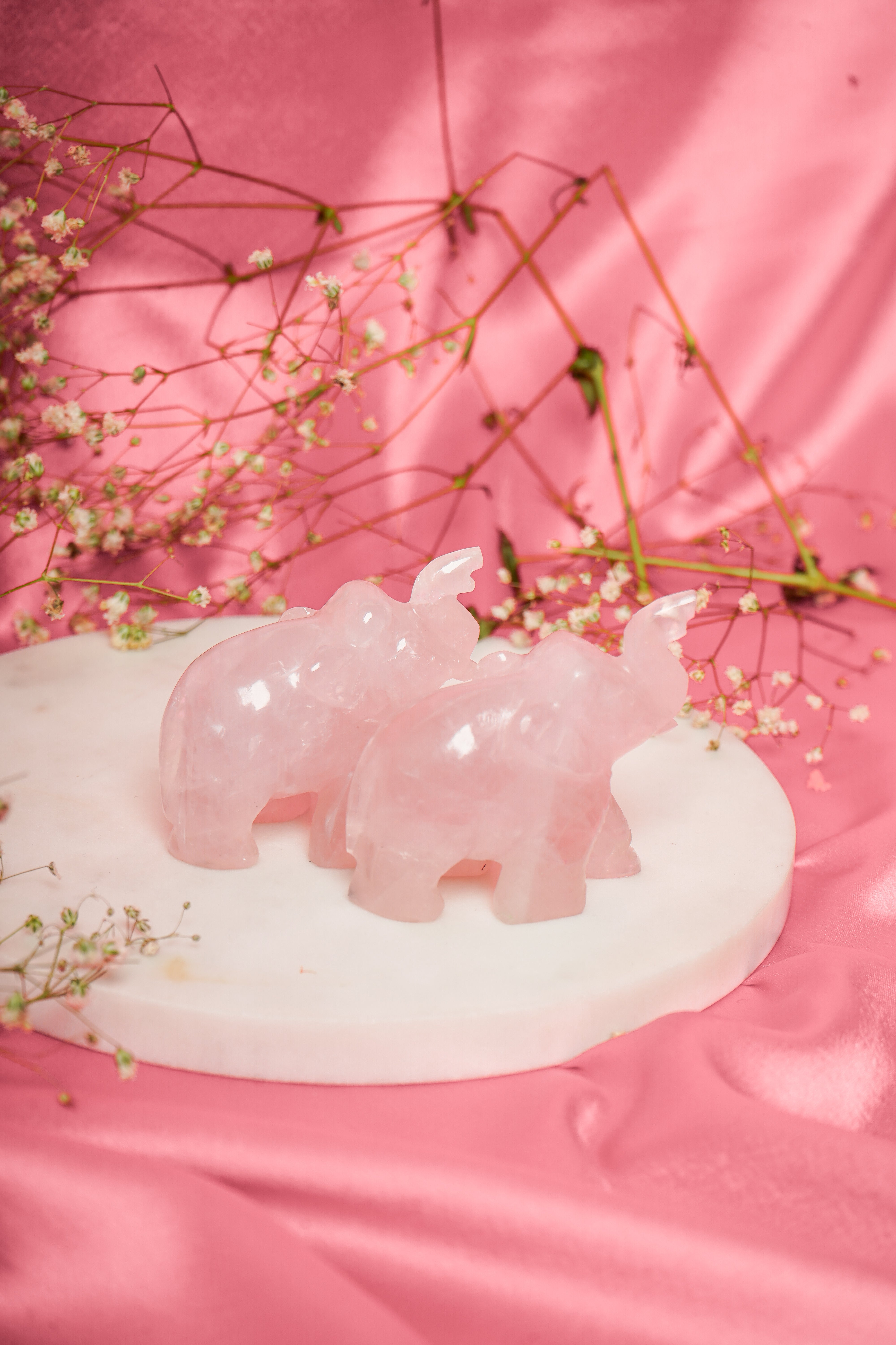 Pair of natural rose quartz elephant figurines, showcasing pink stone details and intricate carvings, ideal for home decor or spiritual purposes.
