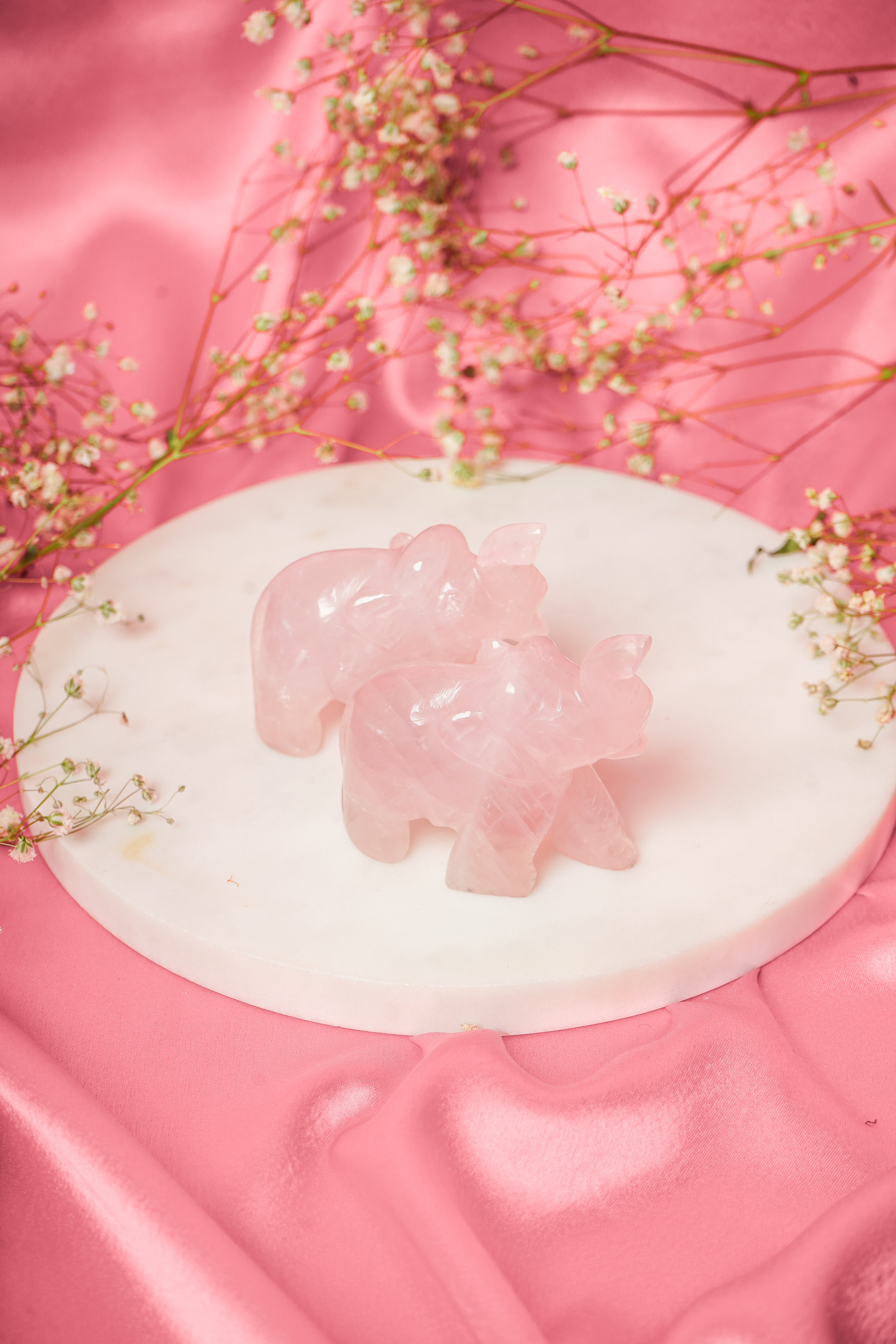 Pair of natural rose quartz elephant figurines with detailed carved features and soft pink hue.