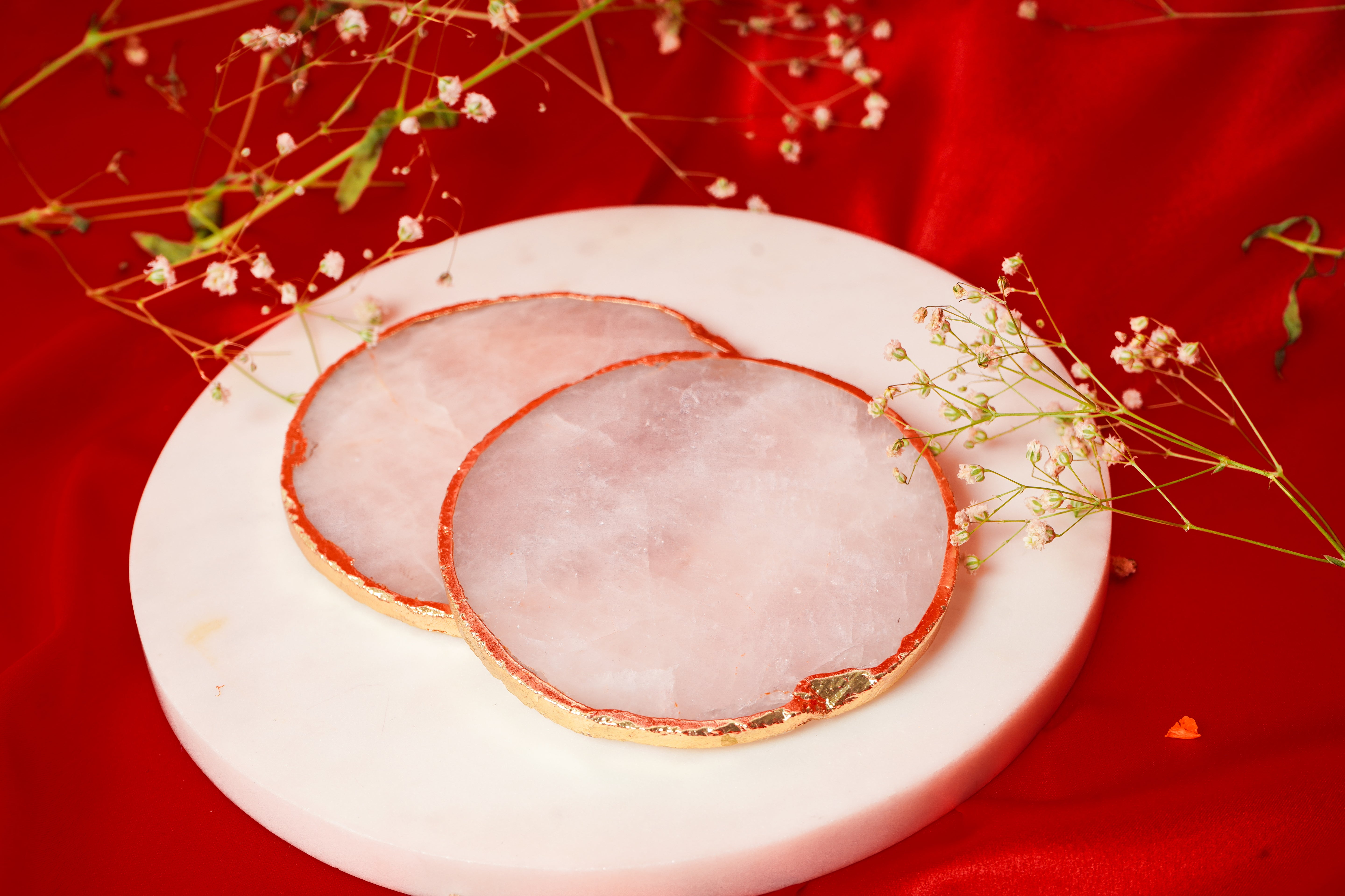 Set of natural rose quartz coasters in a variety of quantities, showcasing smooth, pink gemstone surfaces for protecting tables.