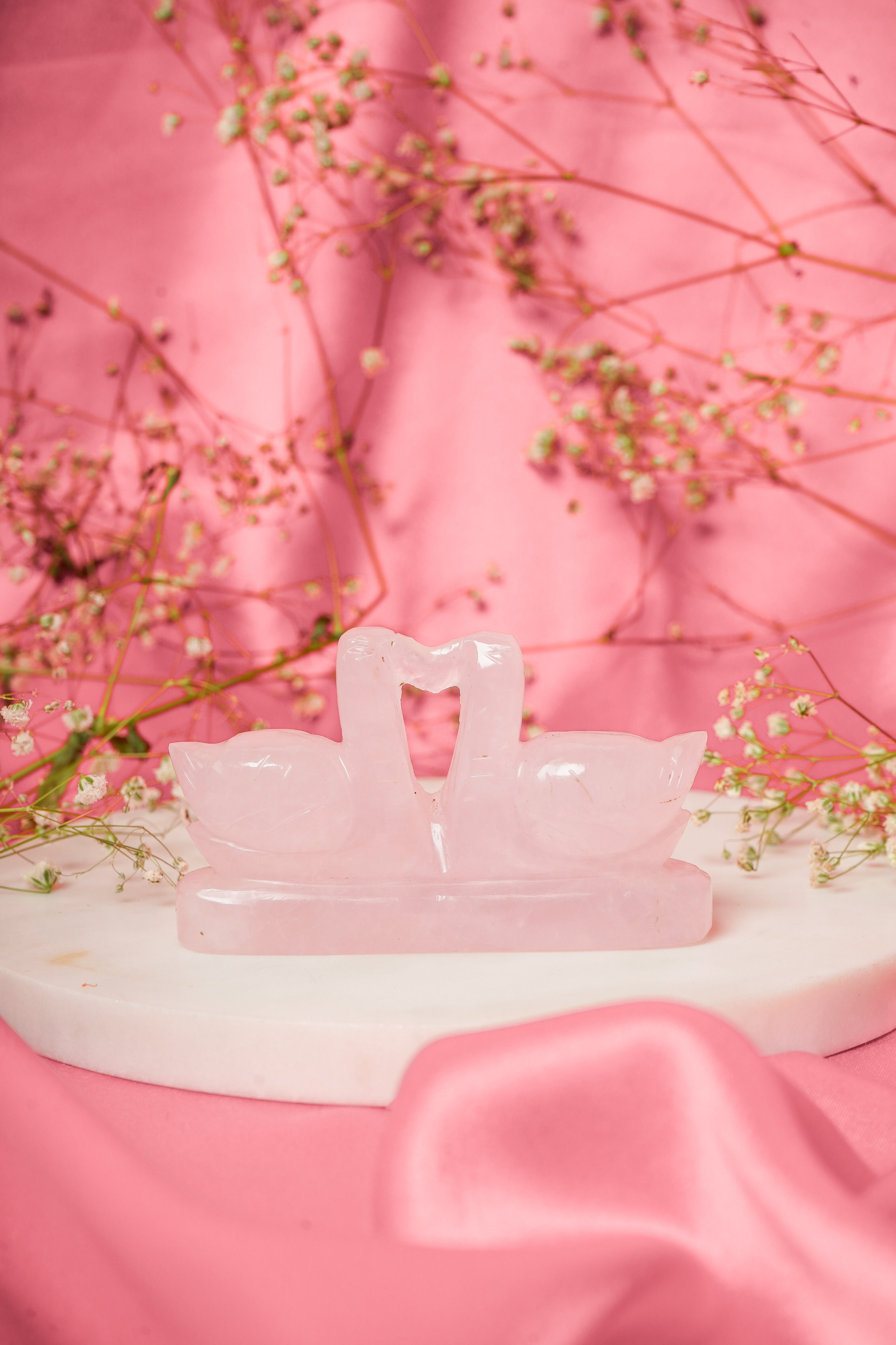 Pair of natural rose quartz swan figurines with smooth polished surfaces, showcasing delicate carved details and soft pink hues.