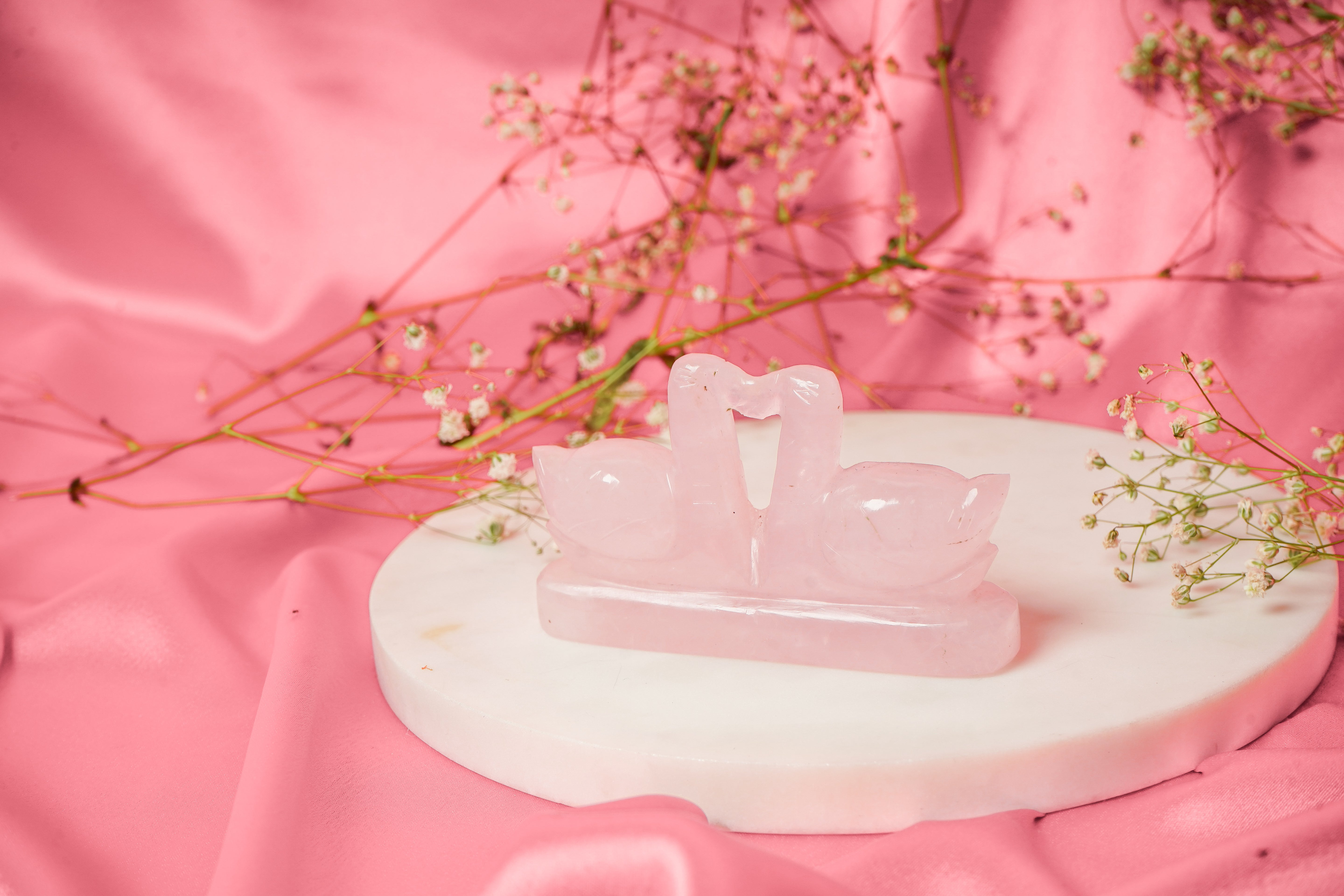 Pair of natural rose quartz swan sculptures with smooth polished surfaces, showcasing elegant craftsmanship and soft pink hues.