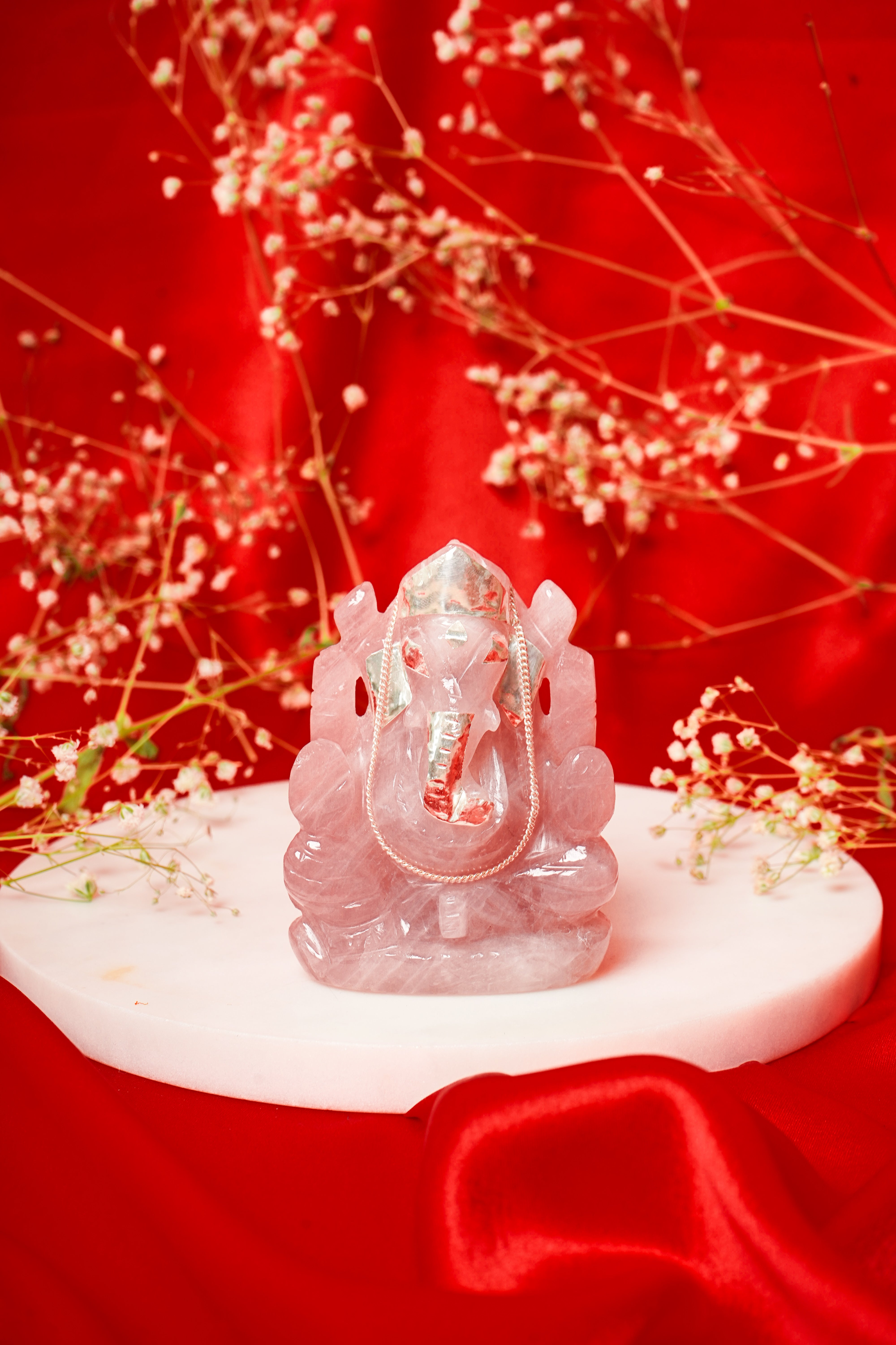 Natural rose quartz Ganesh ji statue with silver accents, featuring intricate carvings and a polished finish.