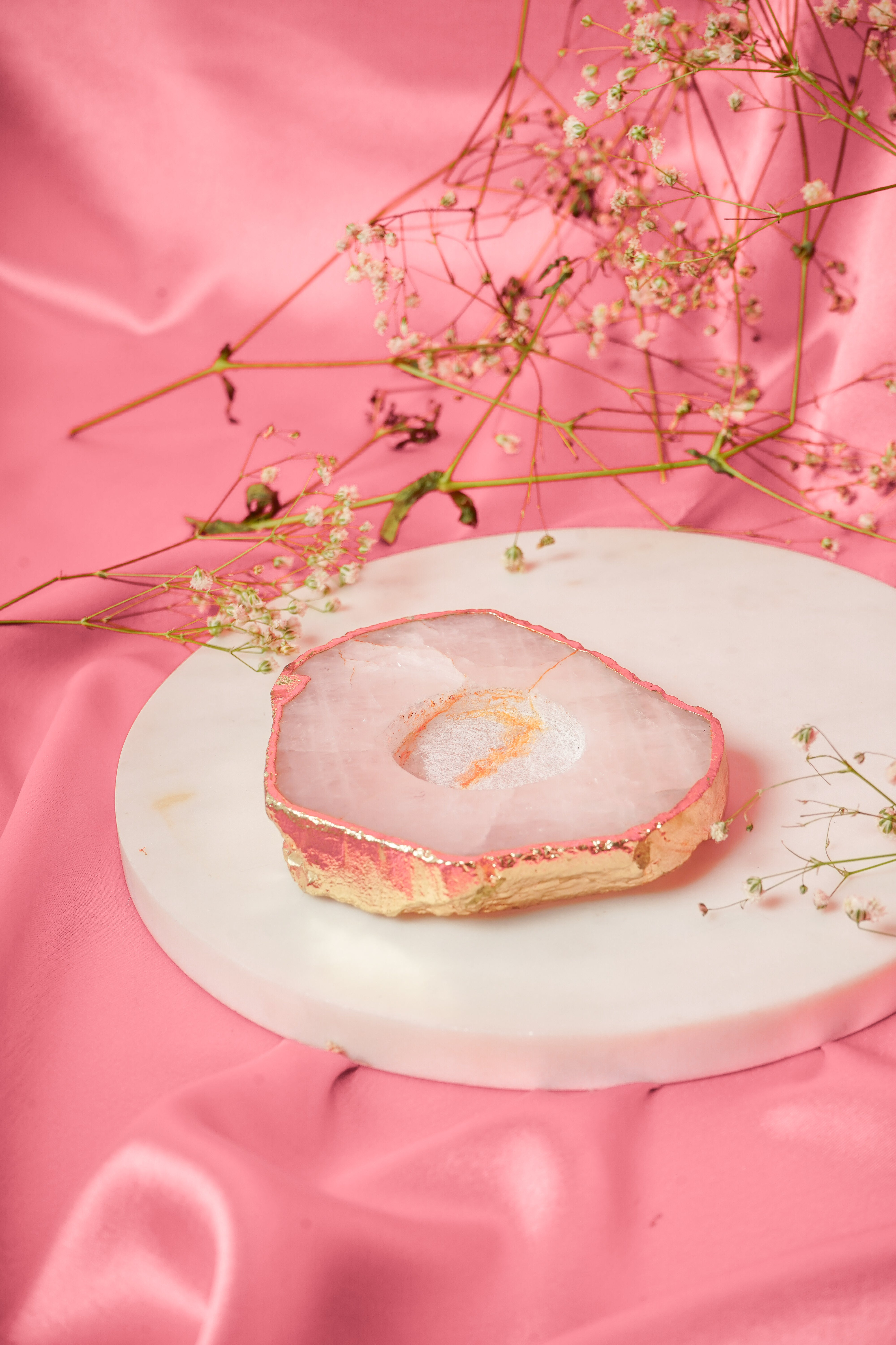 Natural rose quartz tea light candle from Rasava Jewels, showcasing a smooth, pink gemstone with a lit candle inside.