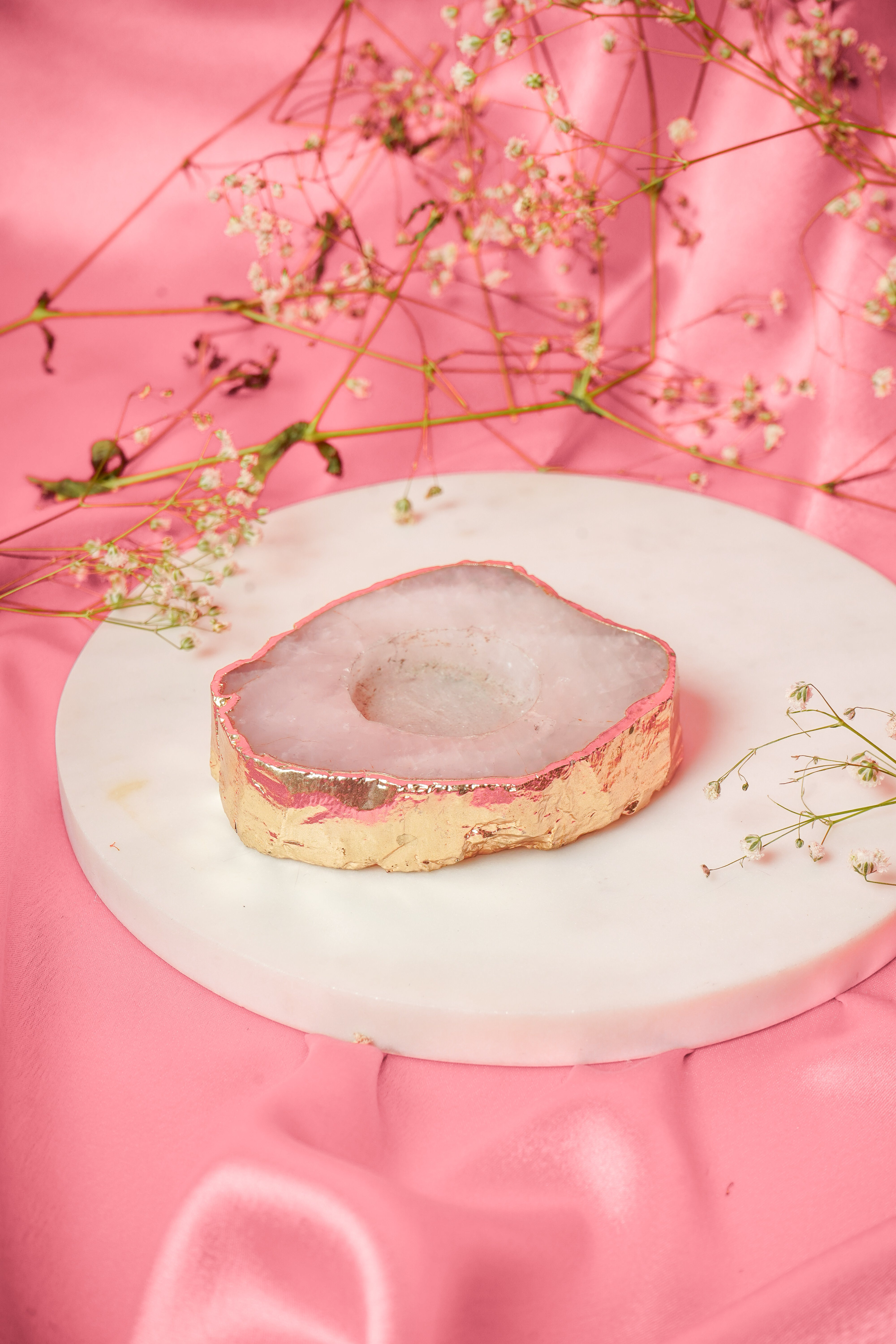 Natural rose quartz tea light candle from Rasava Jewels, showcasing a smooth pink gemstone with a lit candle inside.