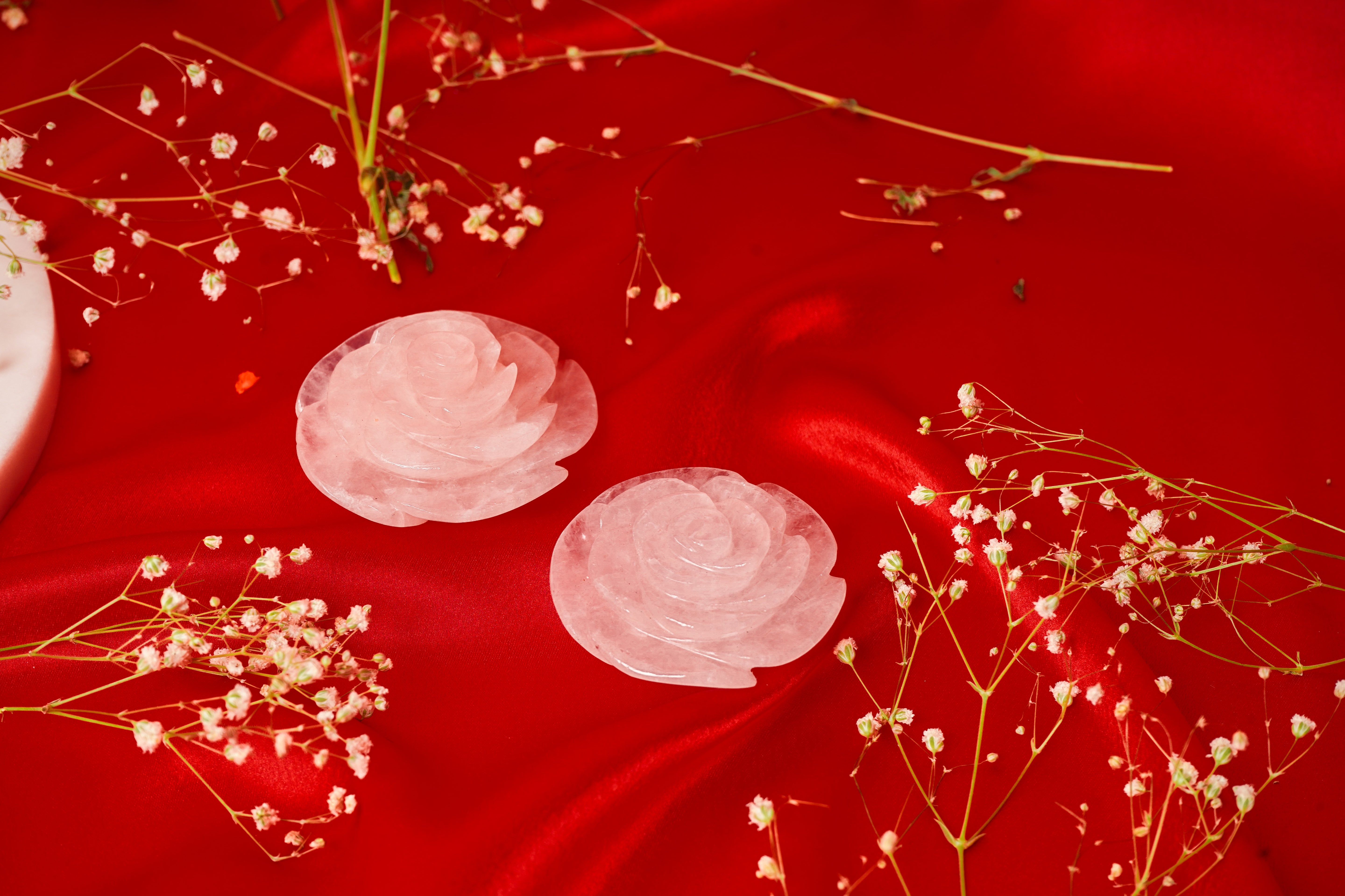 Pair of natural rose quartz rose flowers with soft pink petals and green leaves, crafted for decorative or spiritual use.
