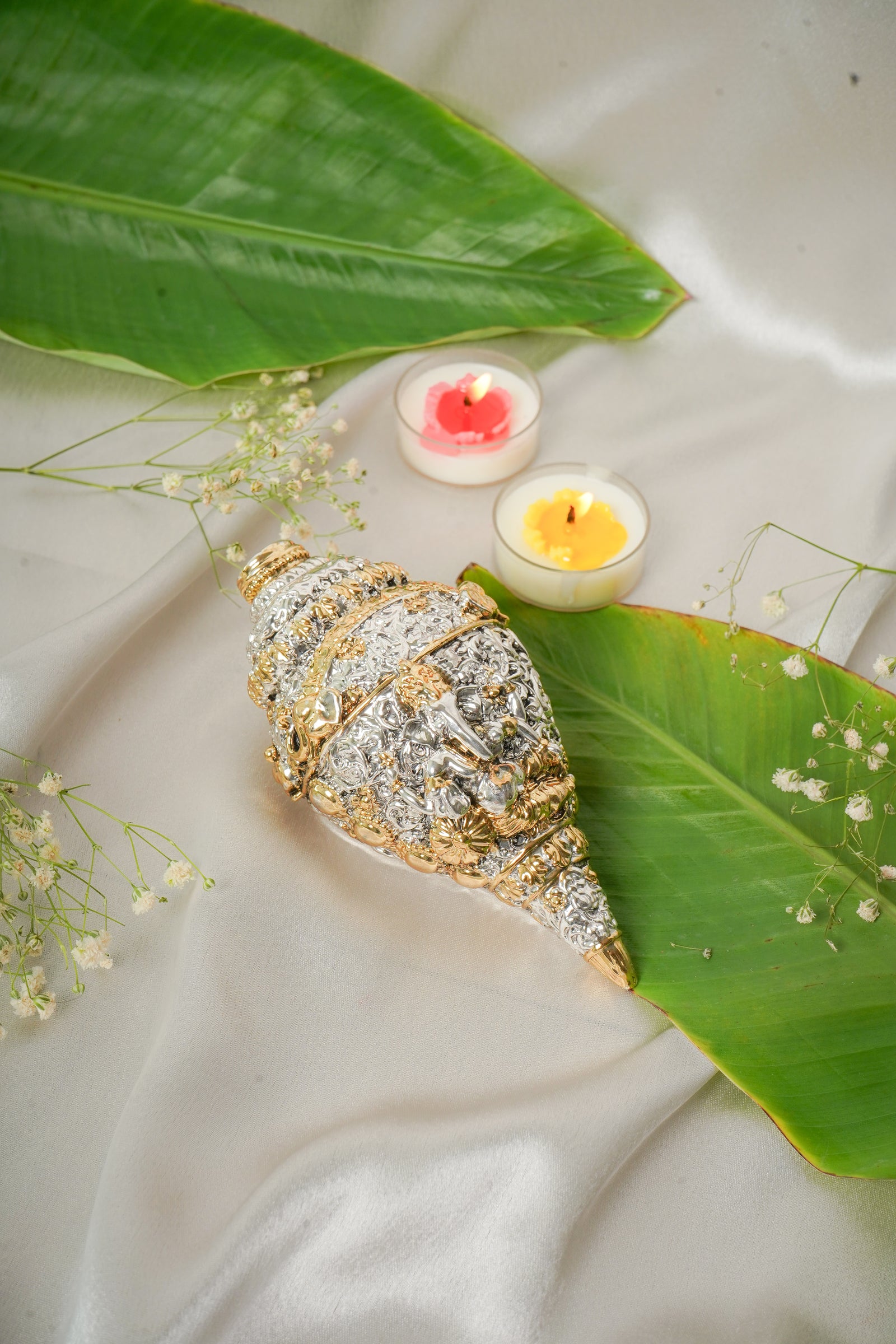 Silver and gold shankh conch shell ornament with intricate design, showcasing traditional craftsmanship.