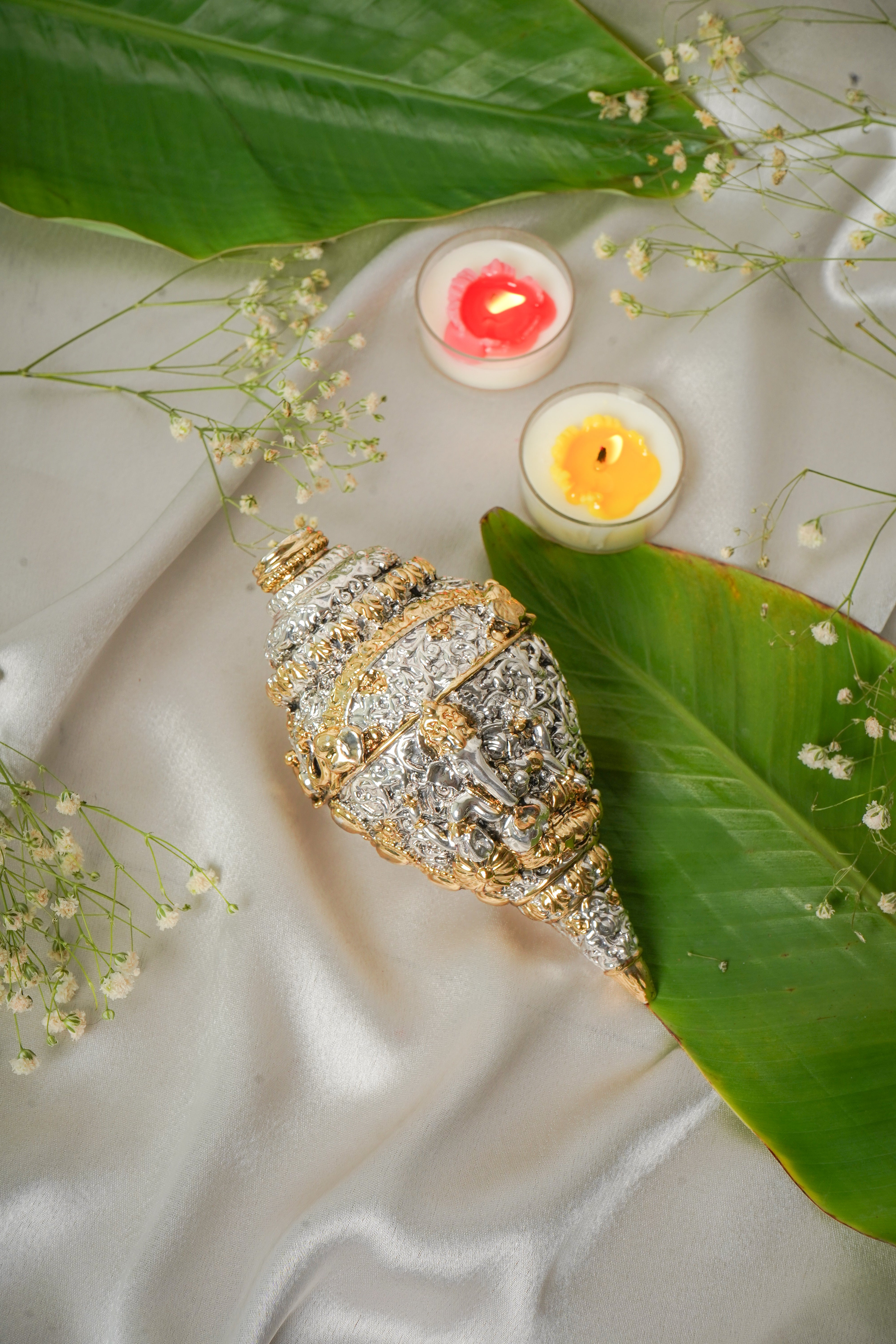Silver and gold shankh conch shell jewelry with intricate design, showcasing shiny metallic finishes and detailed craftsmanship.