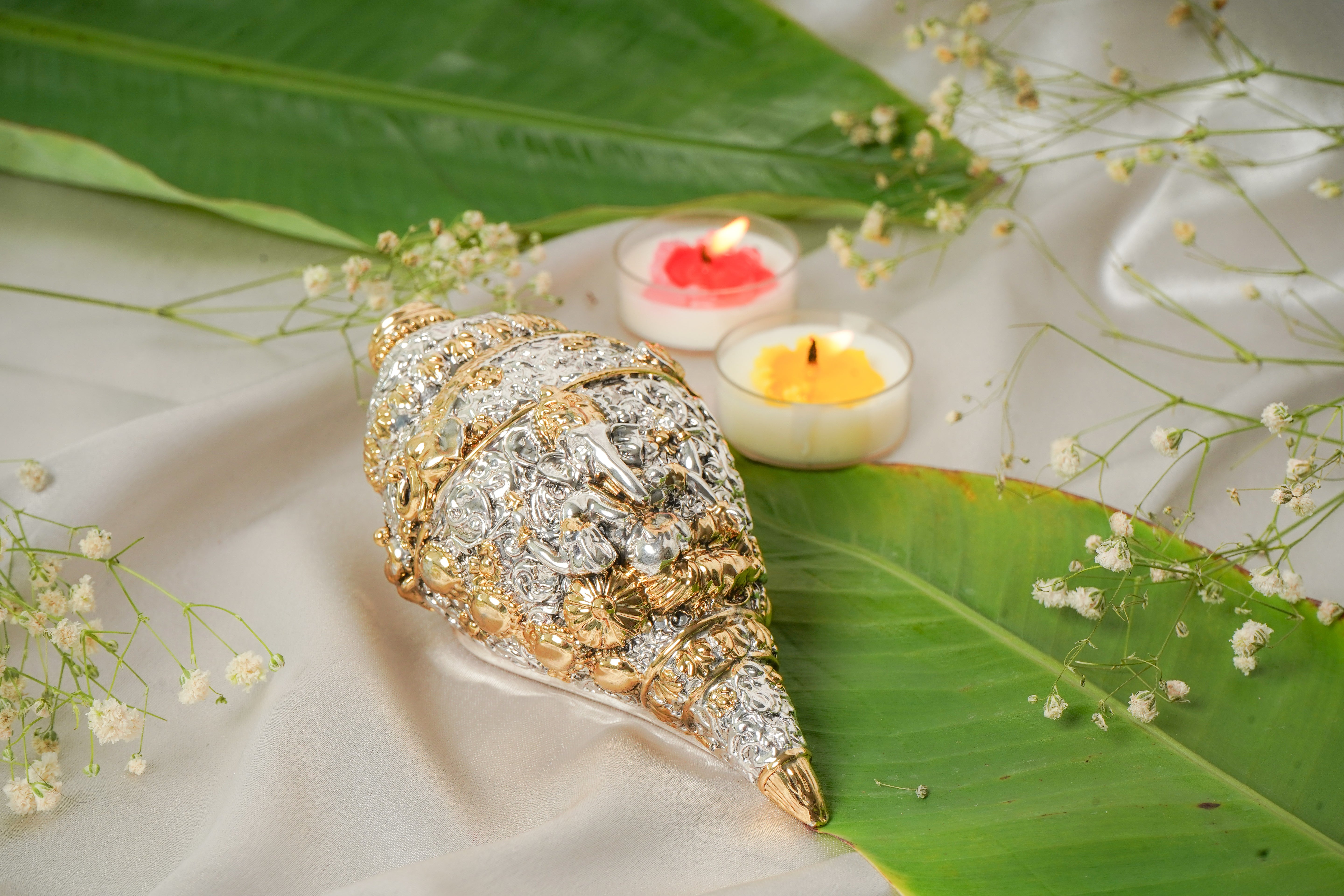 Silver and gold shankh shell with intricate patterns, showcasing a traditional Indian design with shiny metallic finishes.