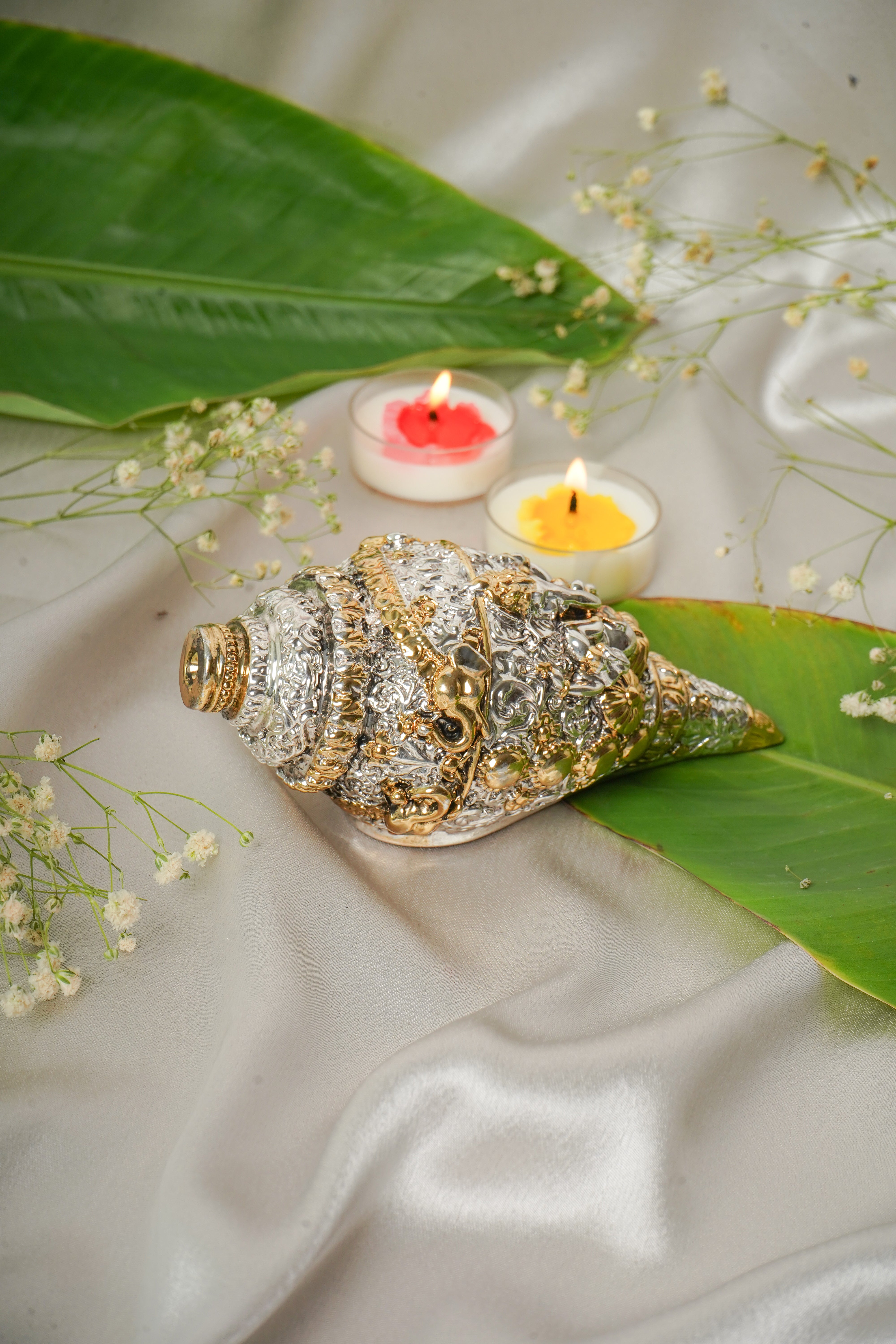 Silver and gold shankh shell with intricate patterns, showcasing traditional design and shiny finish.