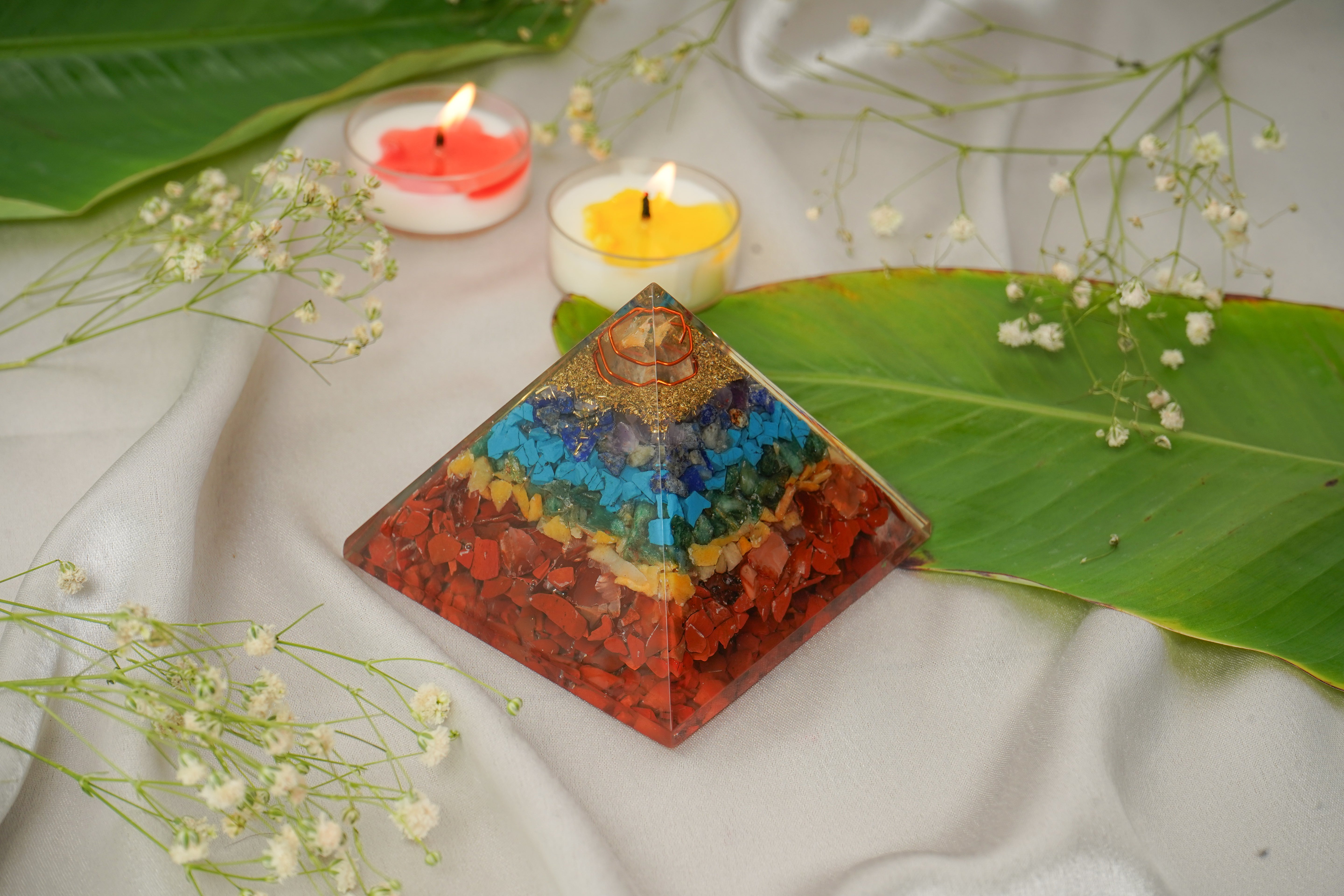 Seven chakra natural stone pyramid with colorful stones arranged in a pyramid shape, showcasing vibrant chakra colors and natural textures.