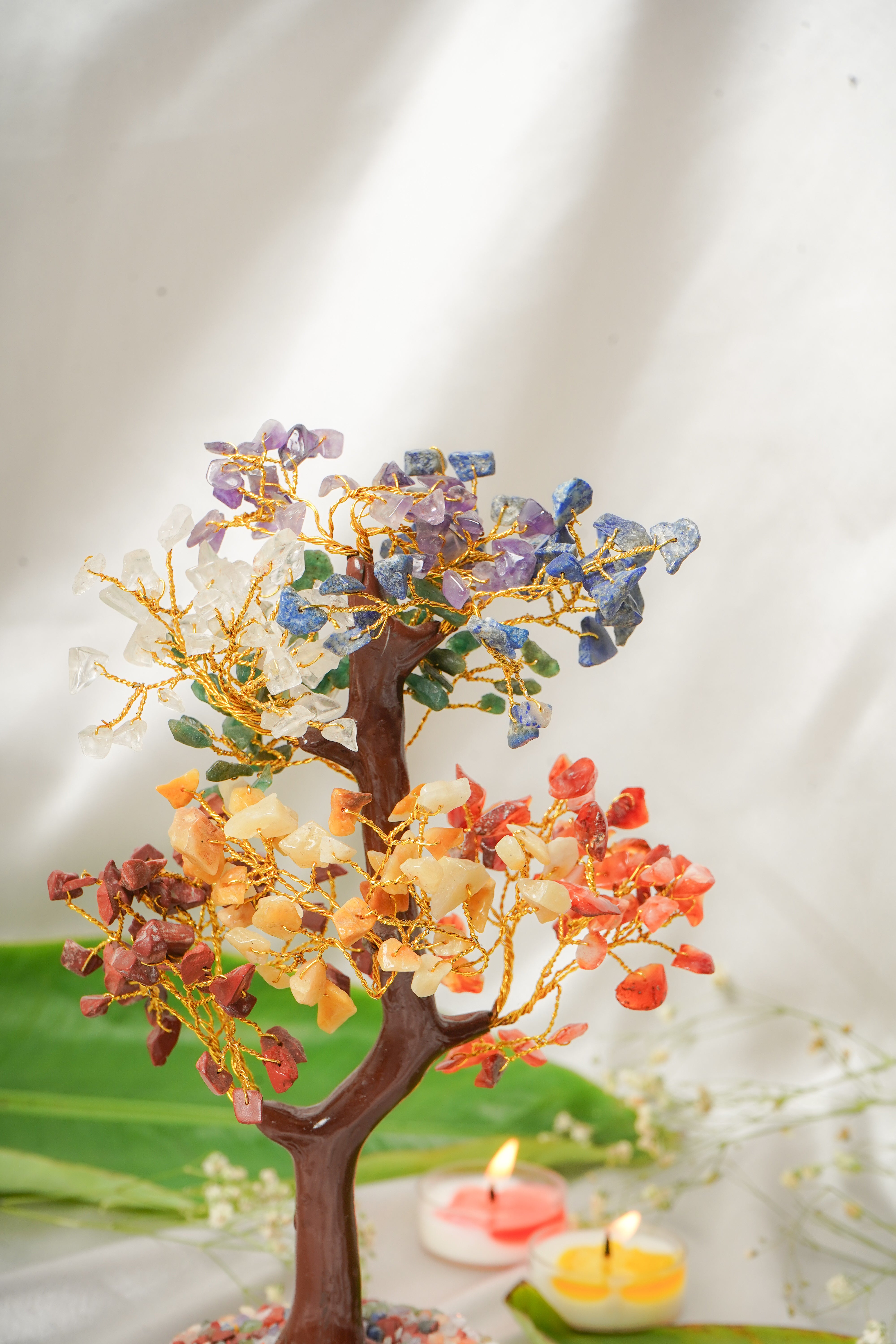 Seven chakra natural stone tree sculpture with colorful stones on a wooden base, representing spiritual energy and harmony.