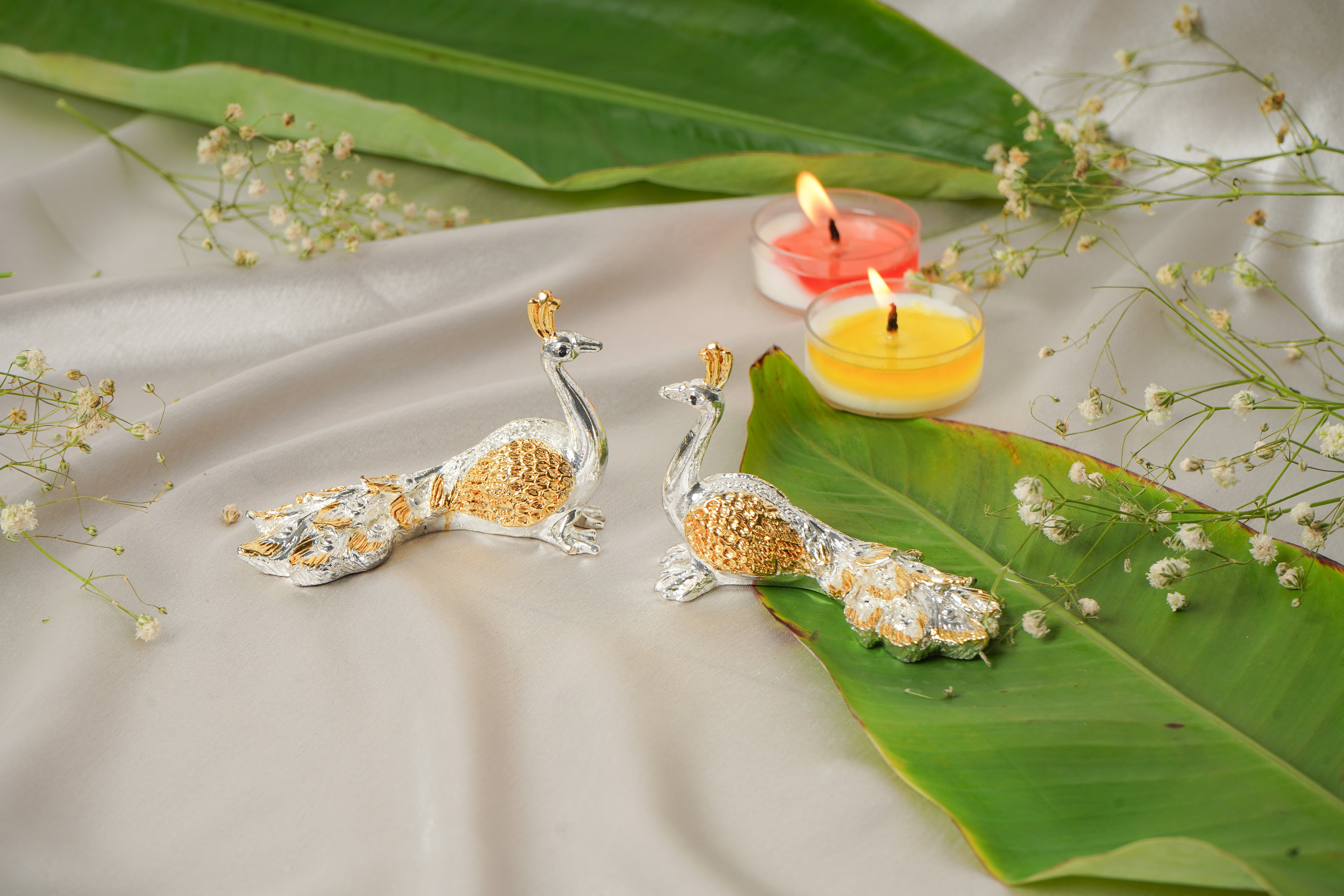 Pair of silver and gold plated peacock earrings with intricate feather details, showcasing elegant jewelry design.