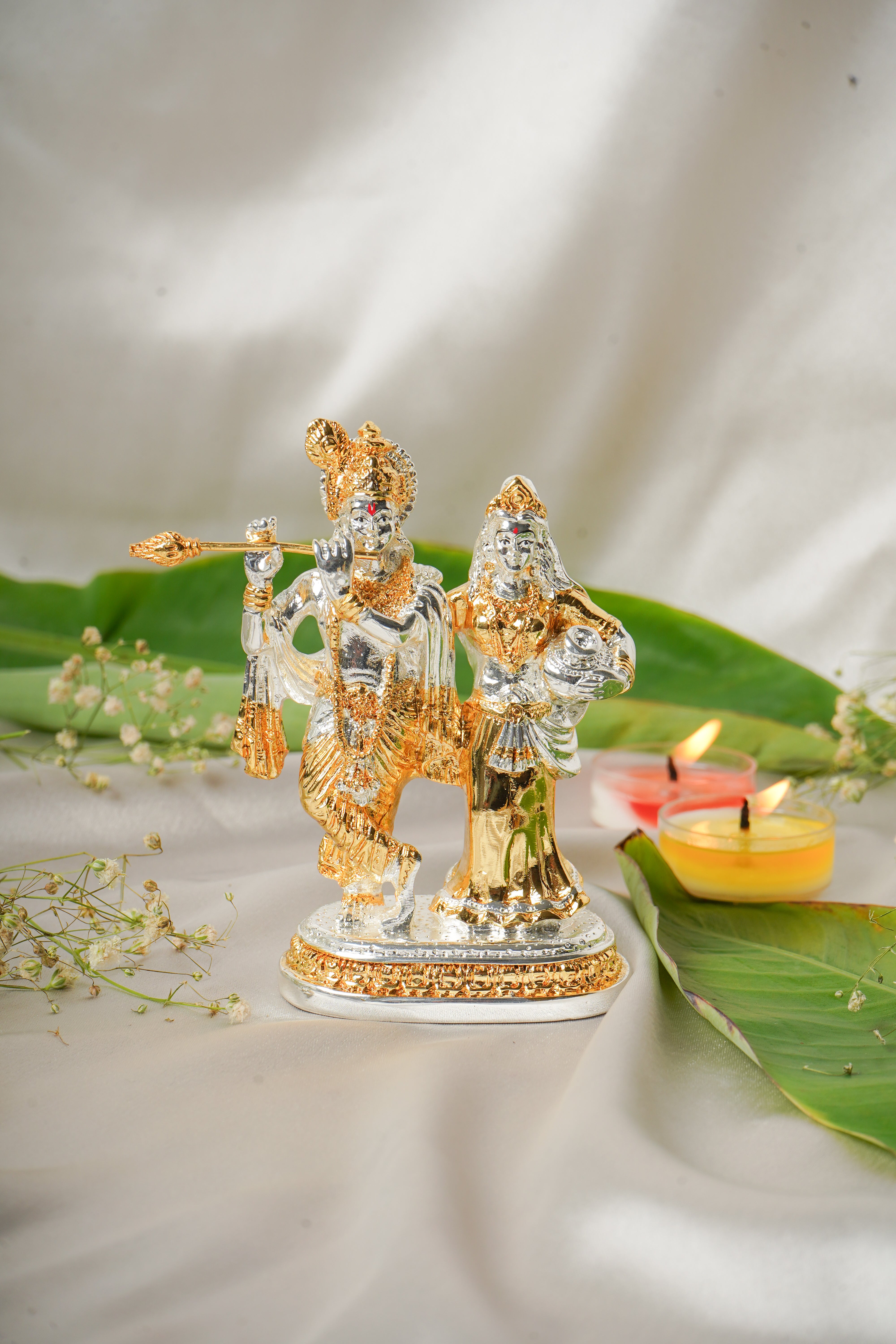 Silver and gold plated Radha Krishna idol with intricate detailing, showcasing divine figures on a decorative base.
