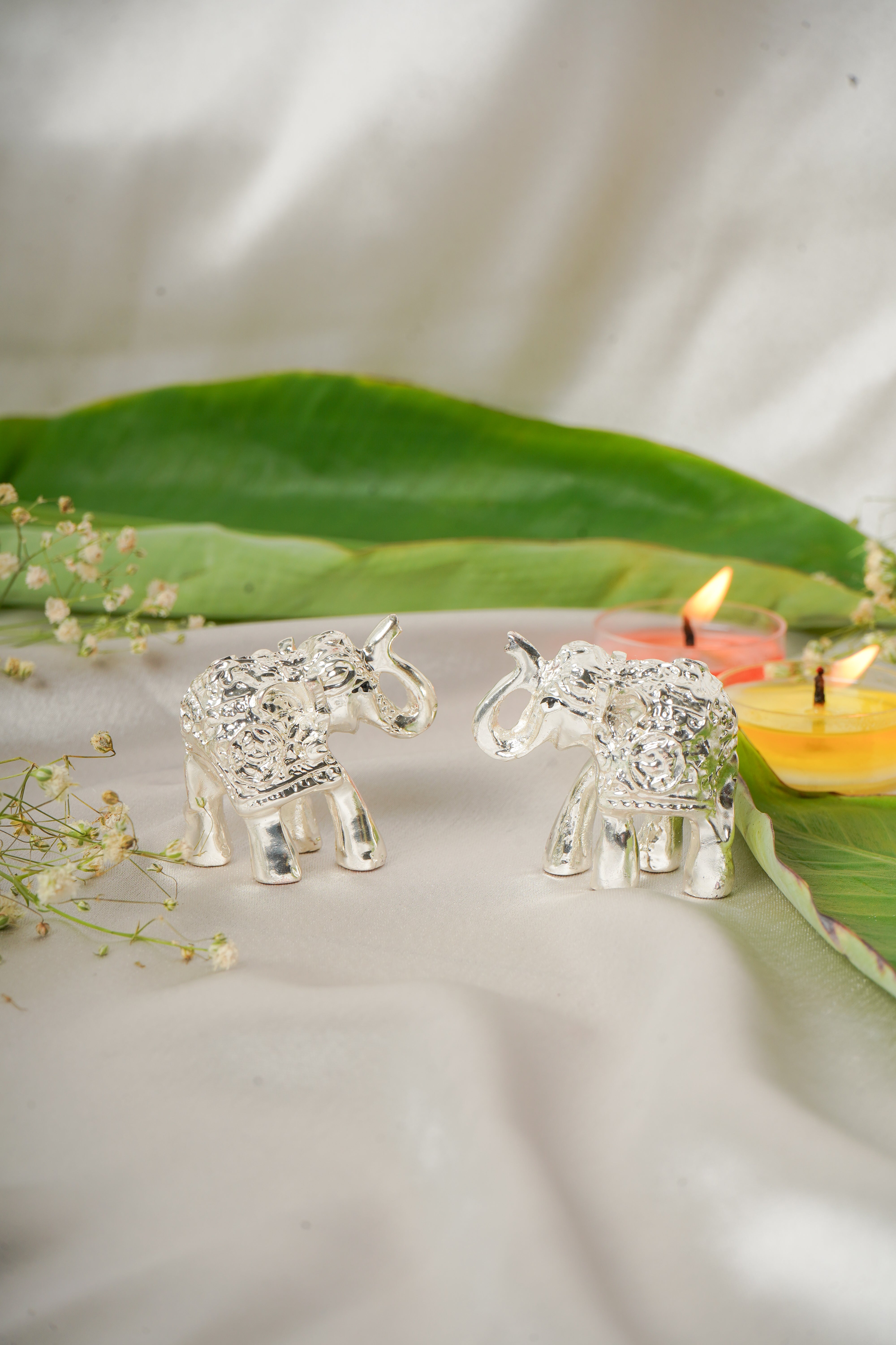 Silver plated elephant pair figurines displayed together, showcasing detailed craftsmanship and shiny silver finish.