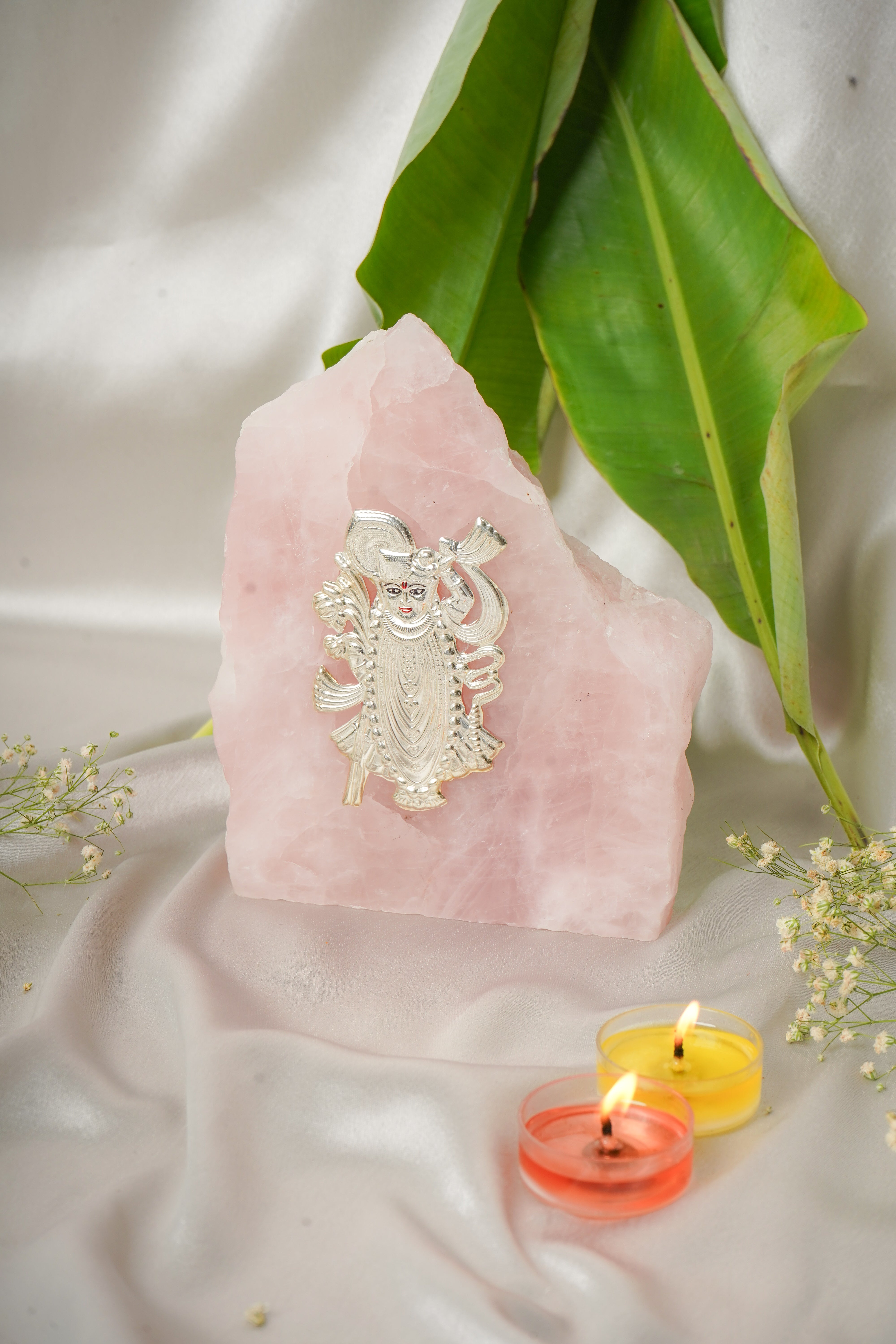 Natural rose quartz stone with pure silver Shrinath Ji idol, showcasing intricate carving and shiny silver details.
