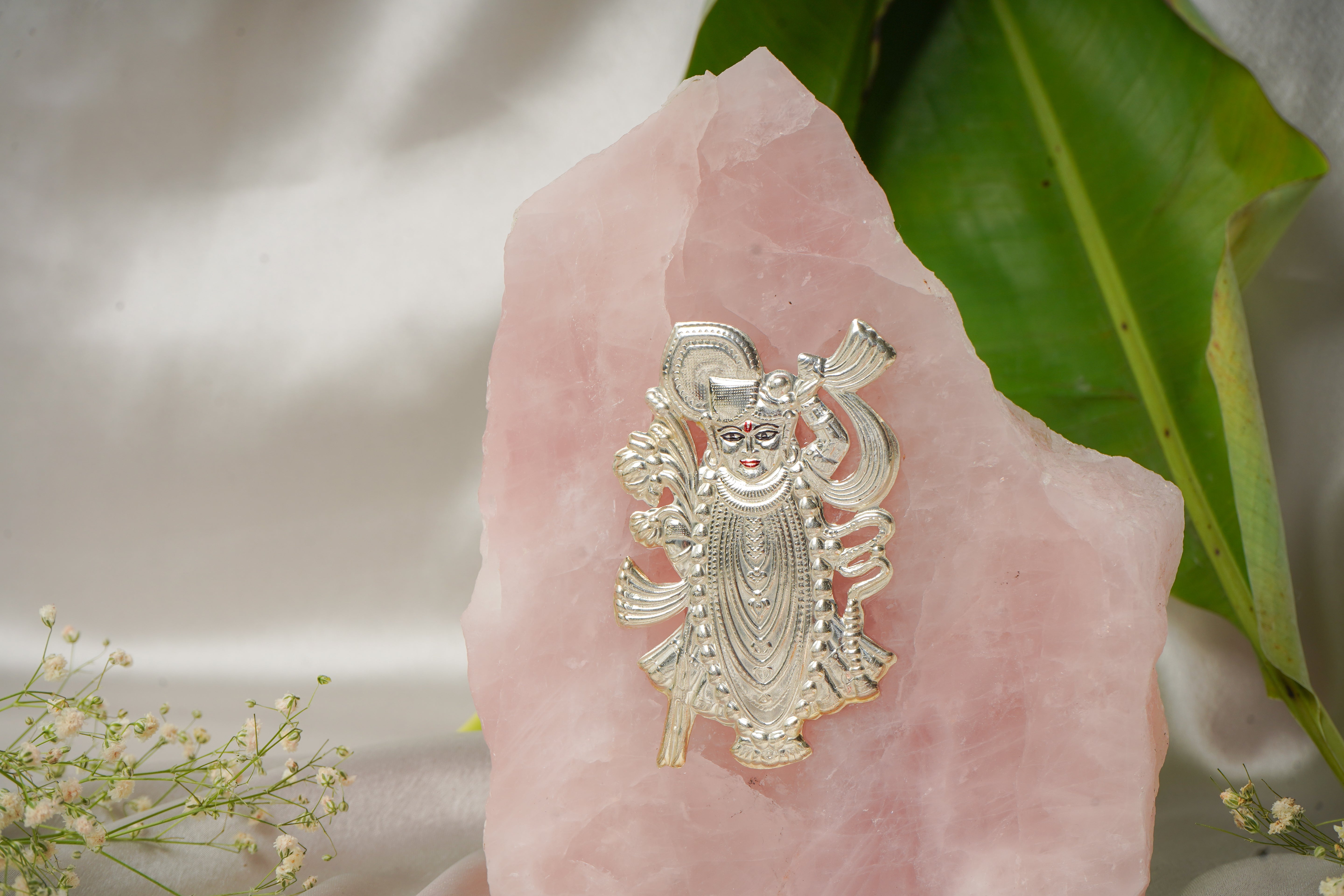 Natural rose quartz stone with pure silver Shrinath ji idol, showcasing detailed craftsmanship and vibrant pink gemstone.