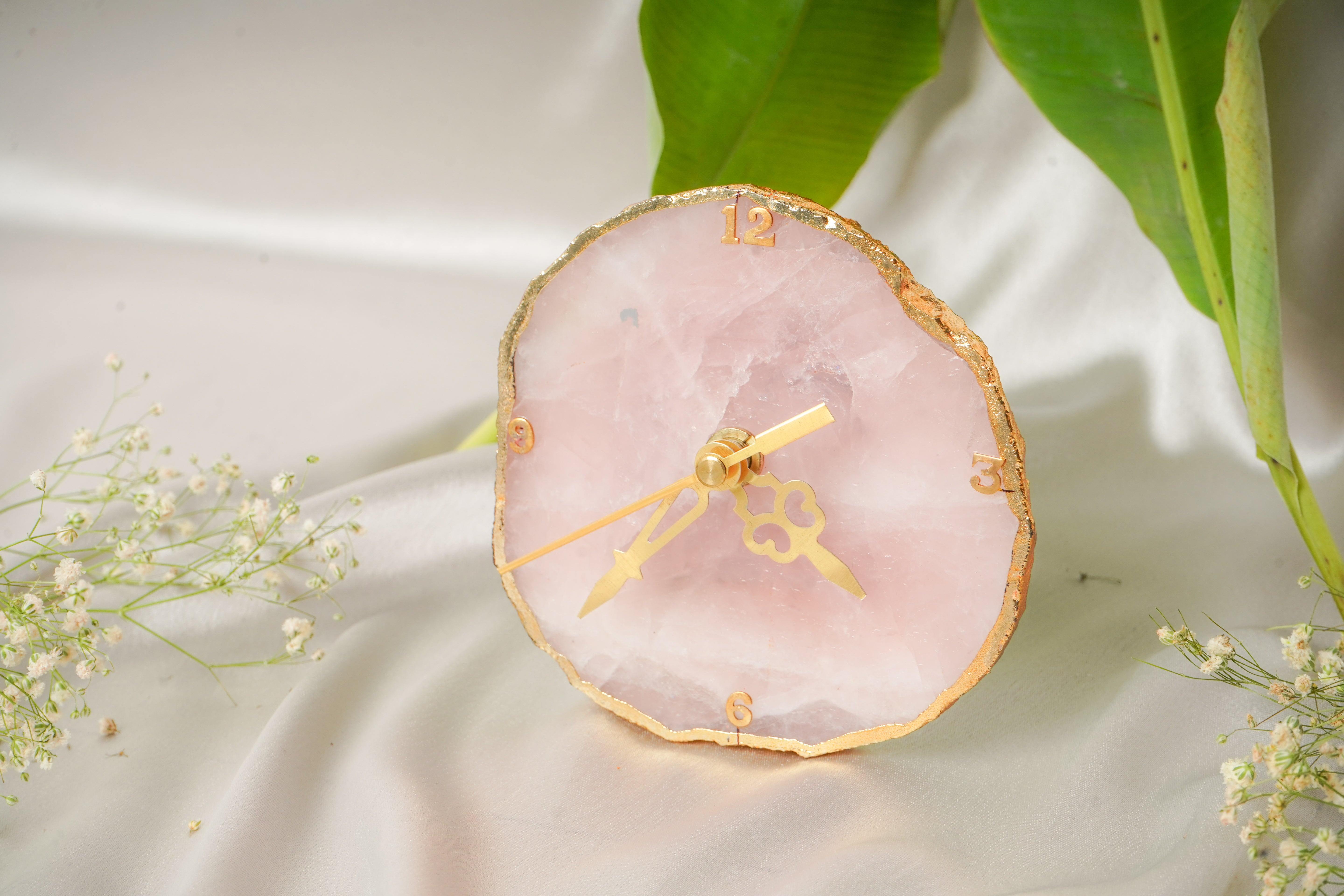 Natural rose quartz table clock with a smooth polished finish, featuring a clear clock face and elegant design.