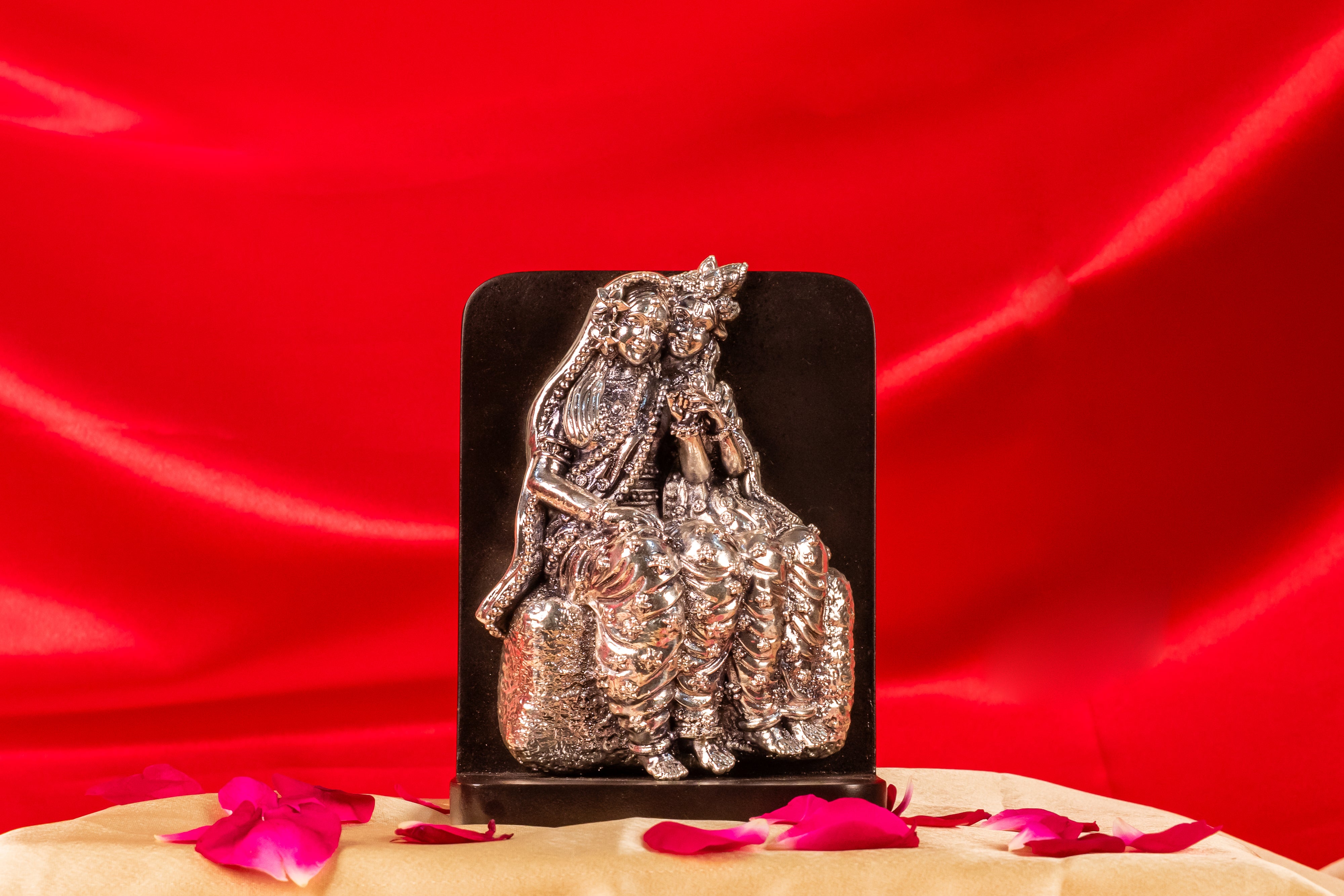 Pure silver Radha Krishna figurine on black base, handcrafted by Rasava Jewels, detailed religious sculpture for spiritual decor.